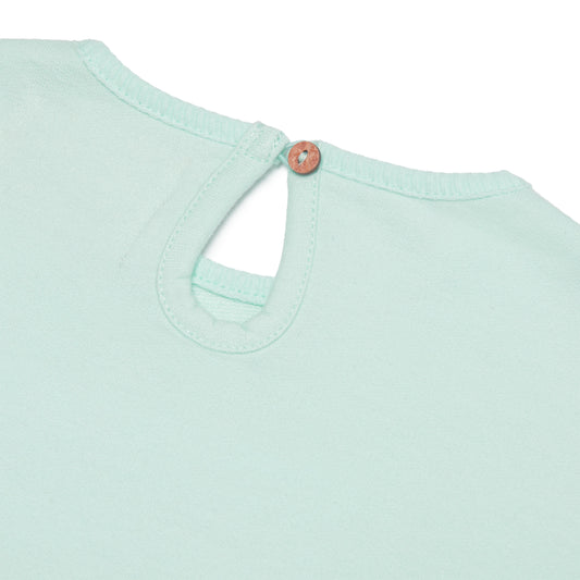 Close-up of a light green shirt with a coconut shell 
button on a white background