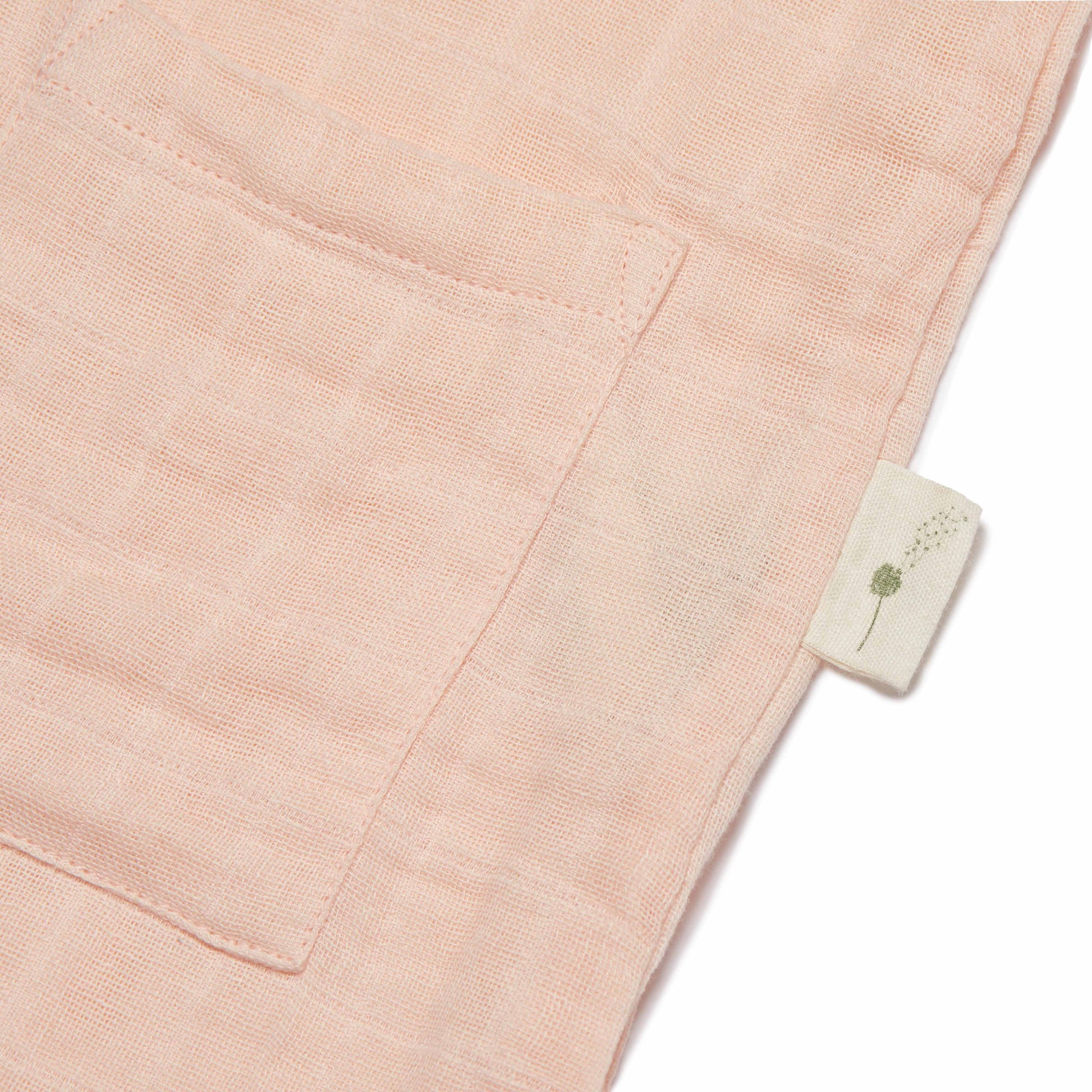 Close-up of a pink fabric with a brand label featuring a dandelion design.