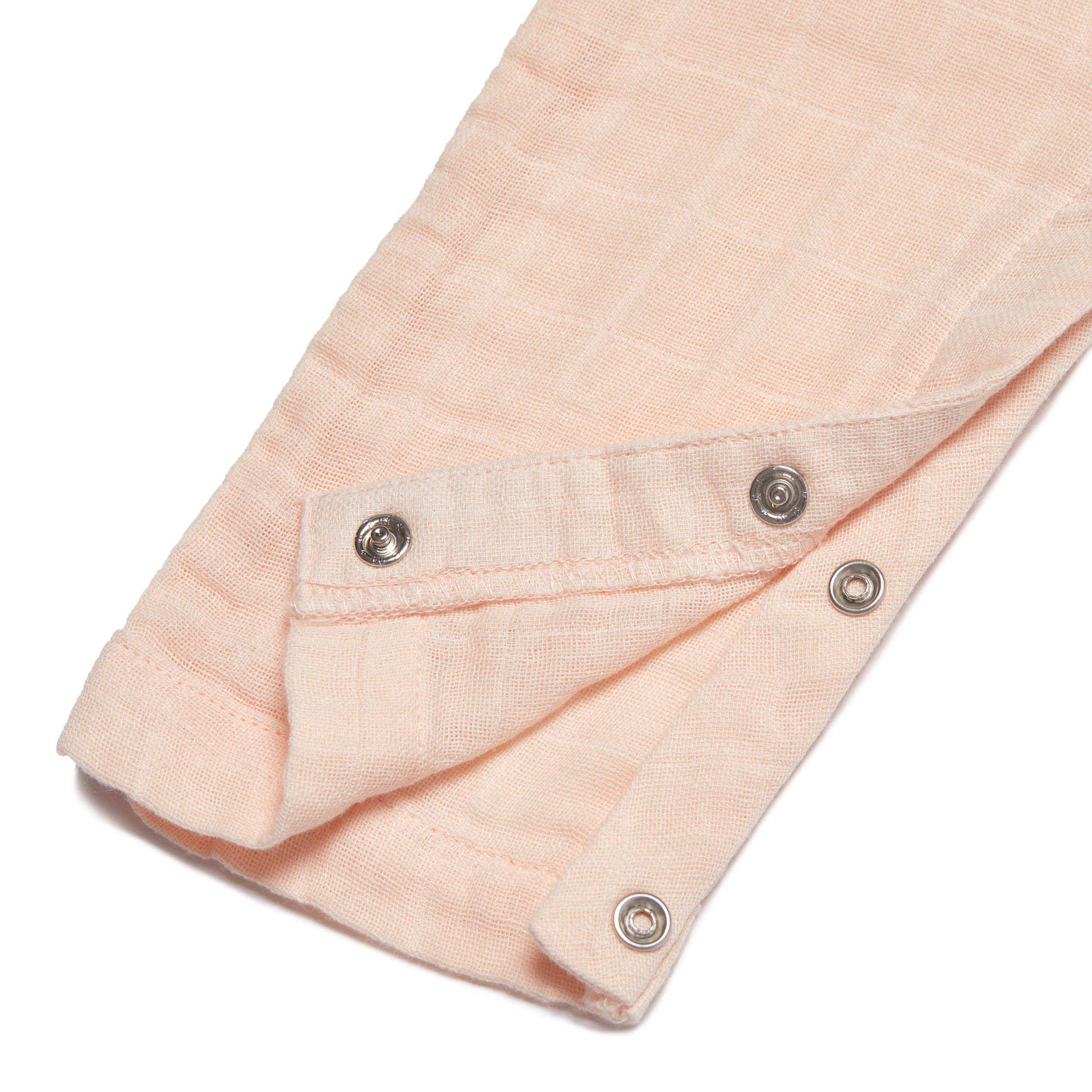 Close-up of a light pink overall with button details on a white background