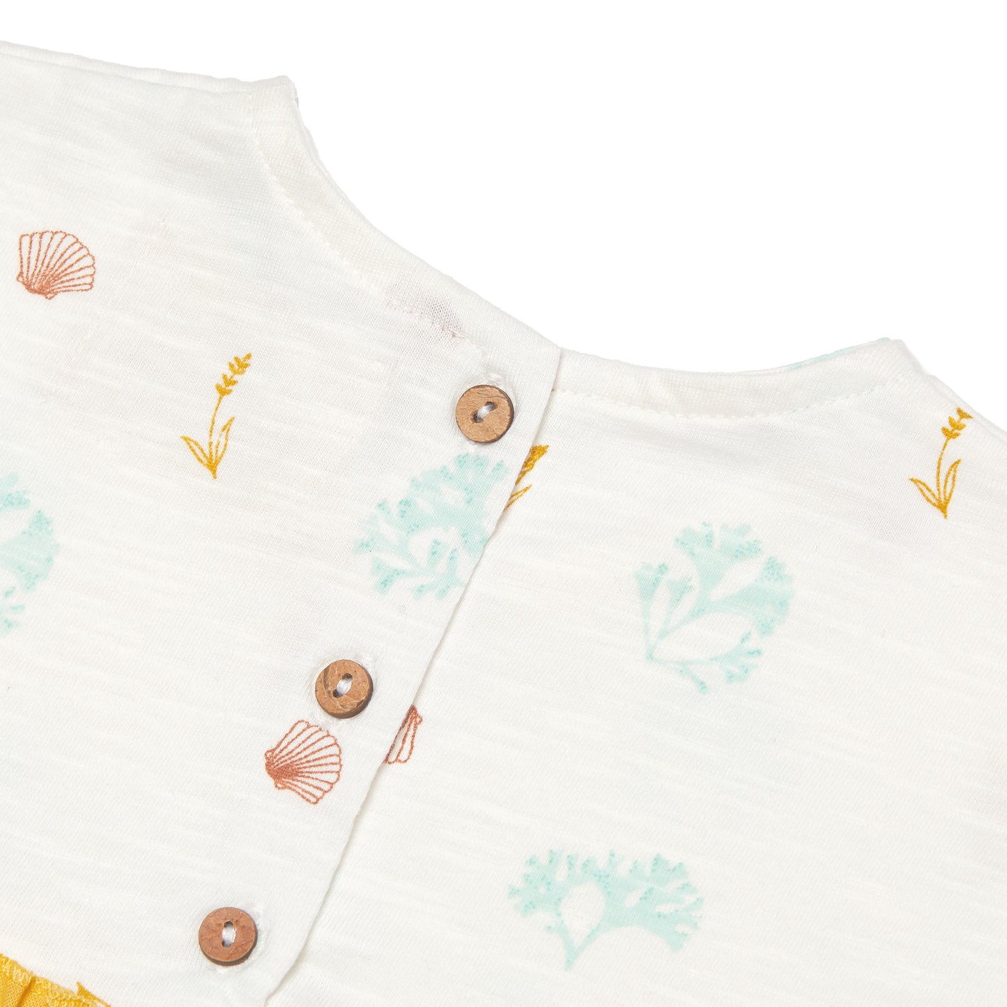 Close-up of a baby outfit with coconut shell buttons and shell patterns on a white background