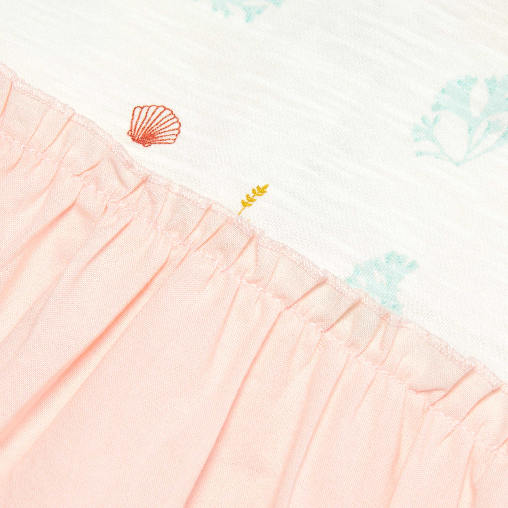 Close-up of a pink fabric with shell  patterns on a white background