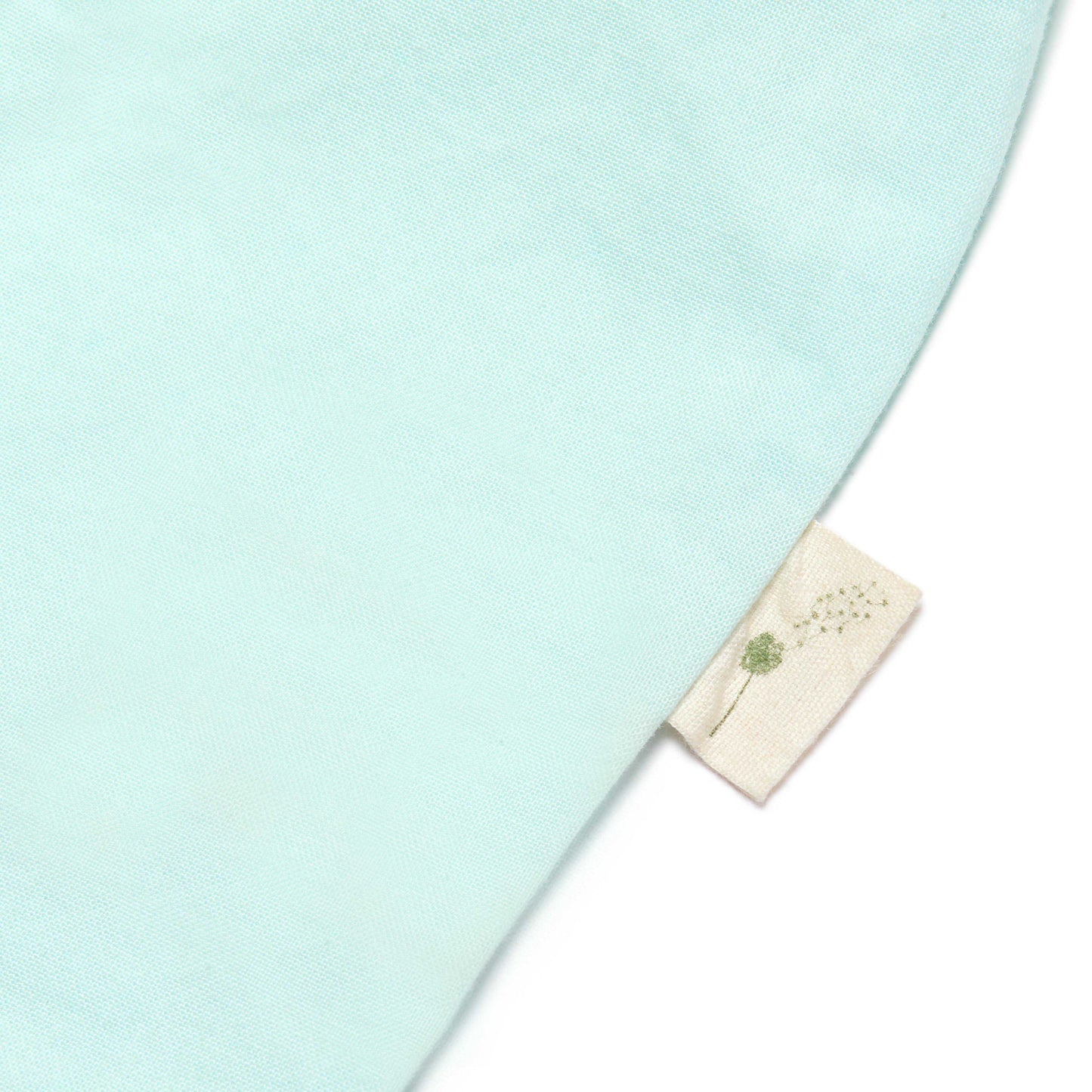 Light blue fabric with a small beige label featuring a dandelion design on a white background